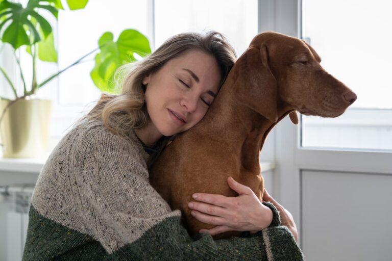Woman hugging a dog by a window